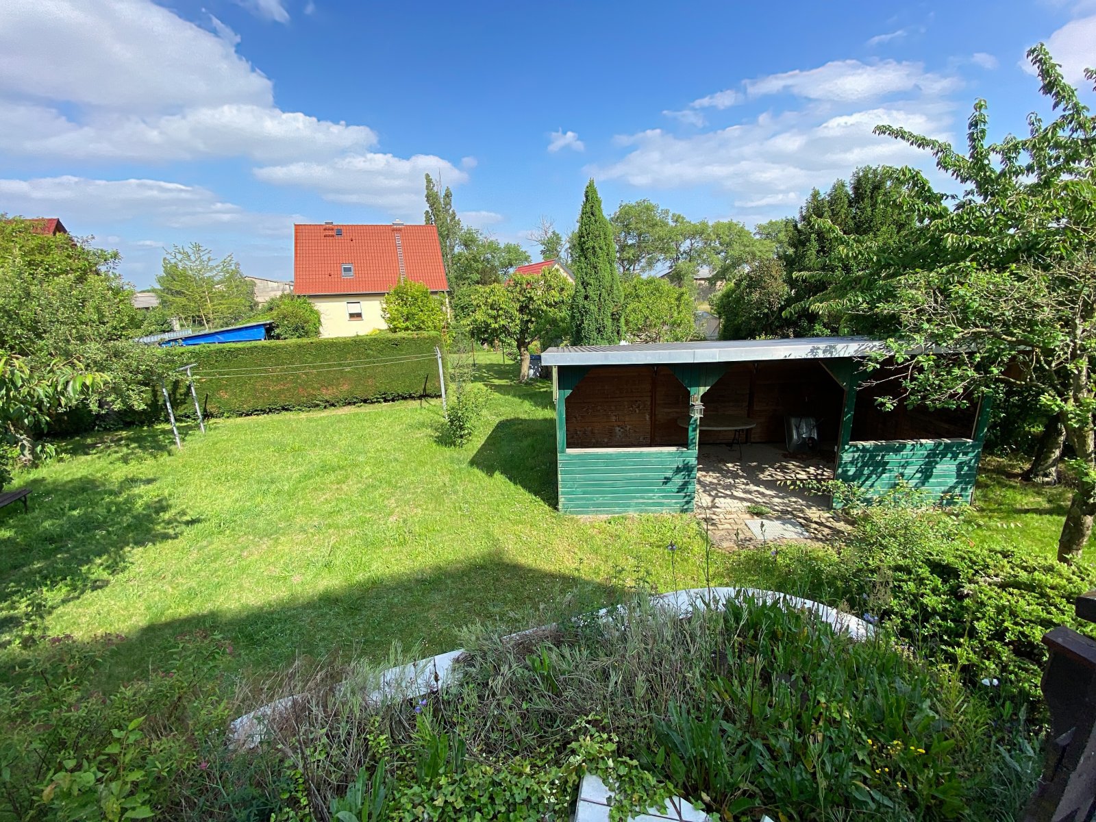 Blick von der Terrasse auf das Grundstück mit überdachtem Freisitz